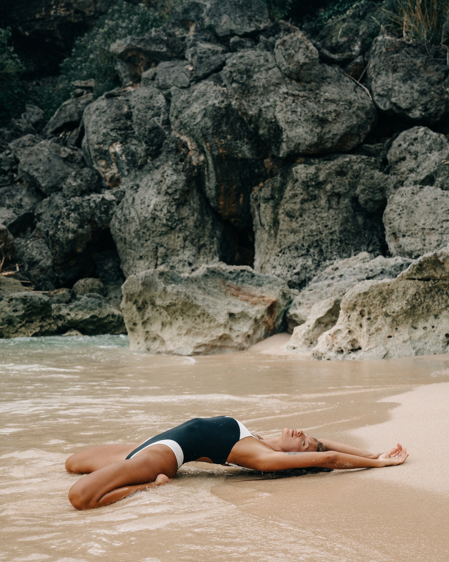 Model resting on shoreline by volcanic rocks